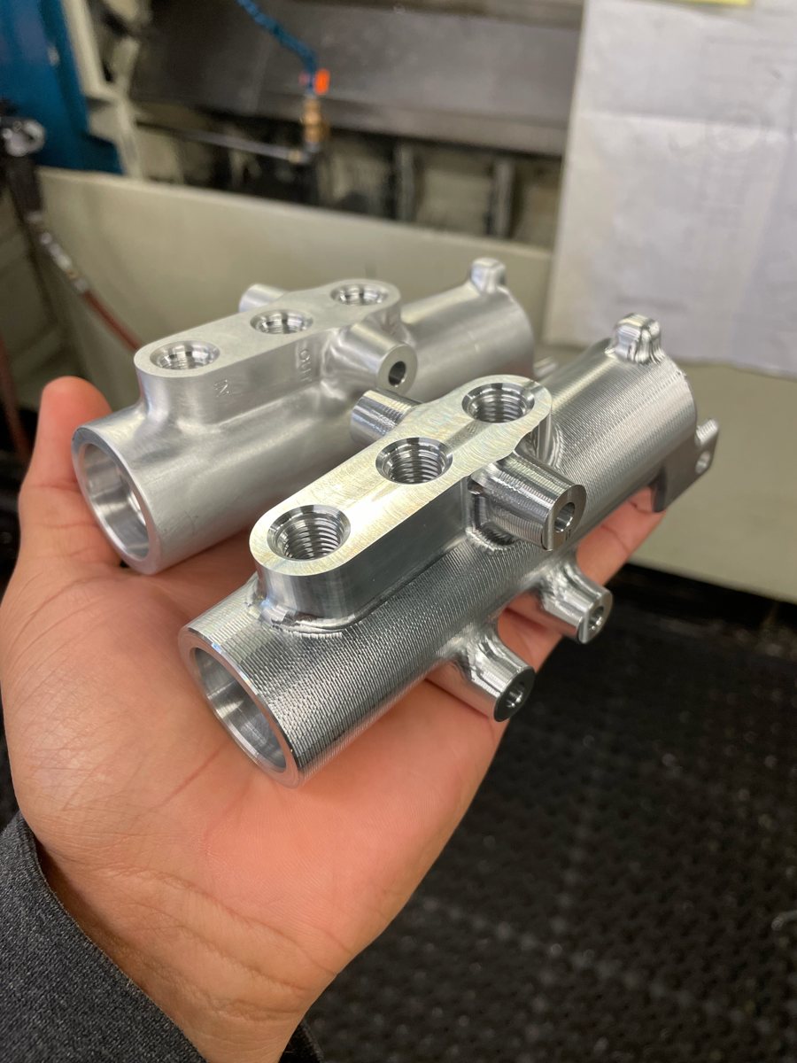 Two machined aluminum manifold blocks held in hand