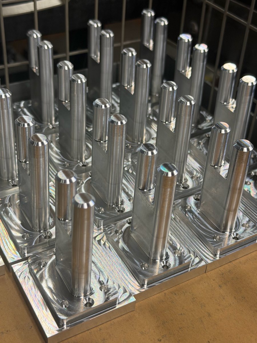 Rows of machined aluminum parts with two round posts each